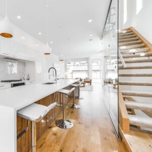 Open concept kitchen and glass staircase by DeanMark Developments